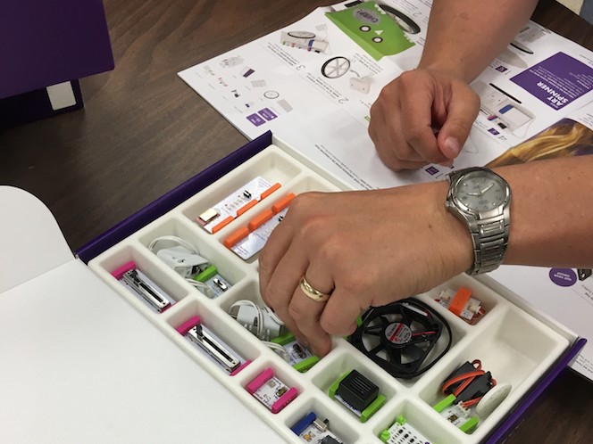 an open box of littleBits with a hand reaching into the box to grab a piece