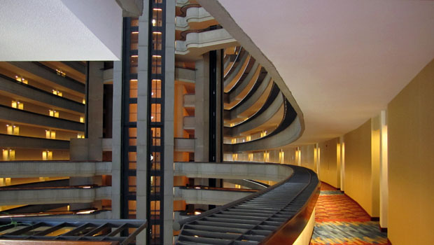 A very bright hotel hallway with an exposed wall that overlooks a number of floors