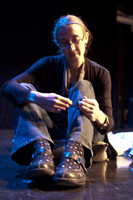 A photo of Melanie, sitting on the floor, playing with elastic bands.