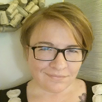 Estee Beck stands in front of a hanging wine cork wreath in background