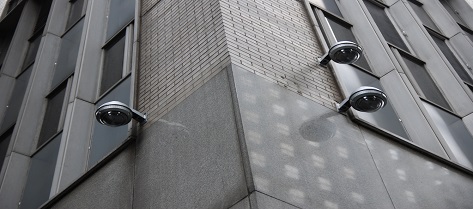 Grayscale of exterior concrete building with three domed cameras