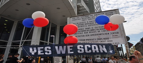 Picture of American consulate board with language of no privacy with activists holding a black banner with white print, yes we scan, in front of the board