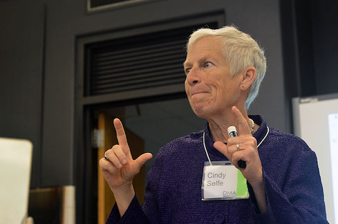 Cindy Selfe gesturing with both hands, holding a marker in her left hand