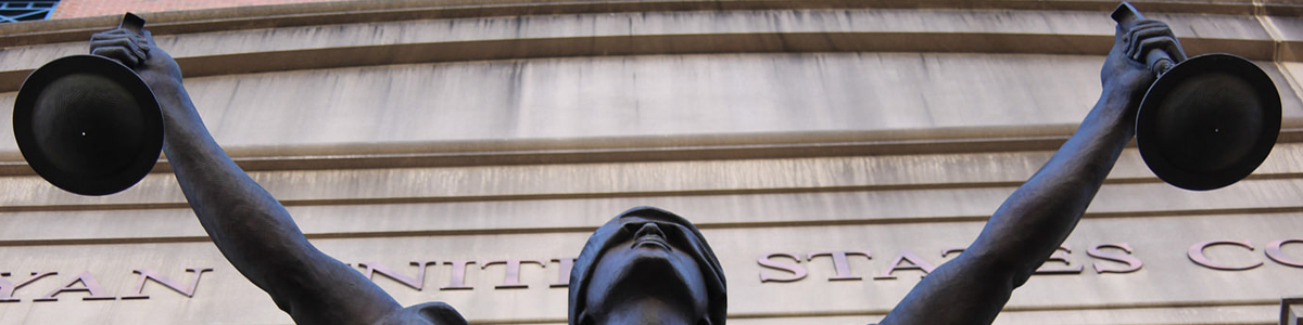 An image depicts a
              copper sculpture of Lady Justice, blindfolded and holding
              one scale in each hand outside of a courthouse.