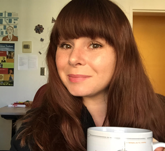 A headshot depicts
                    Les sitting before a well posted wall holding a
                    robust cup of coffee.